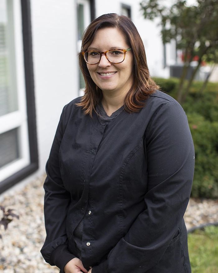 Portrait of Amber, Dental Assistant from the waist up. Woman in black uniform.