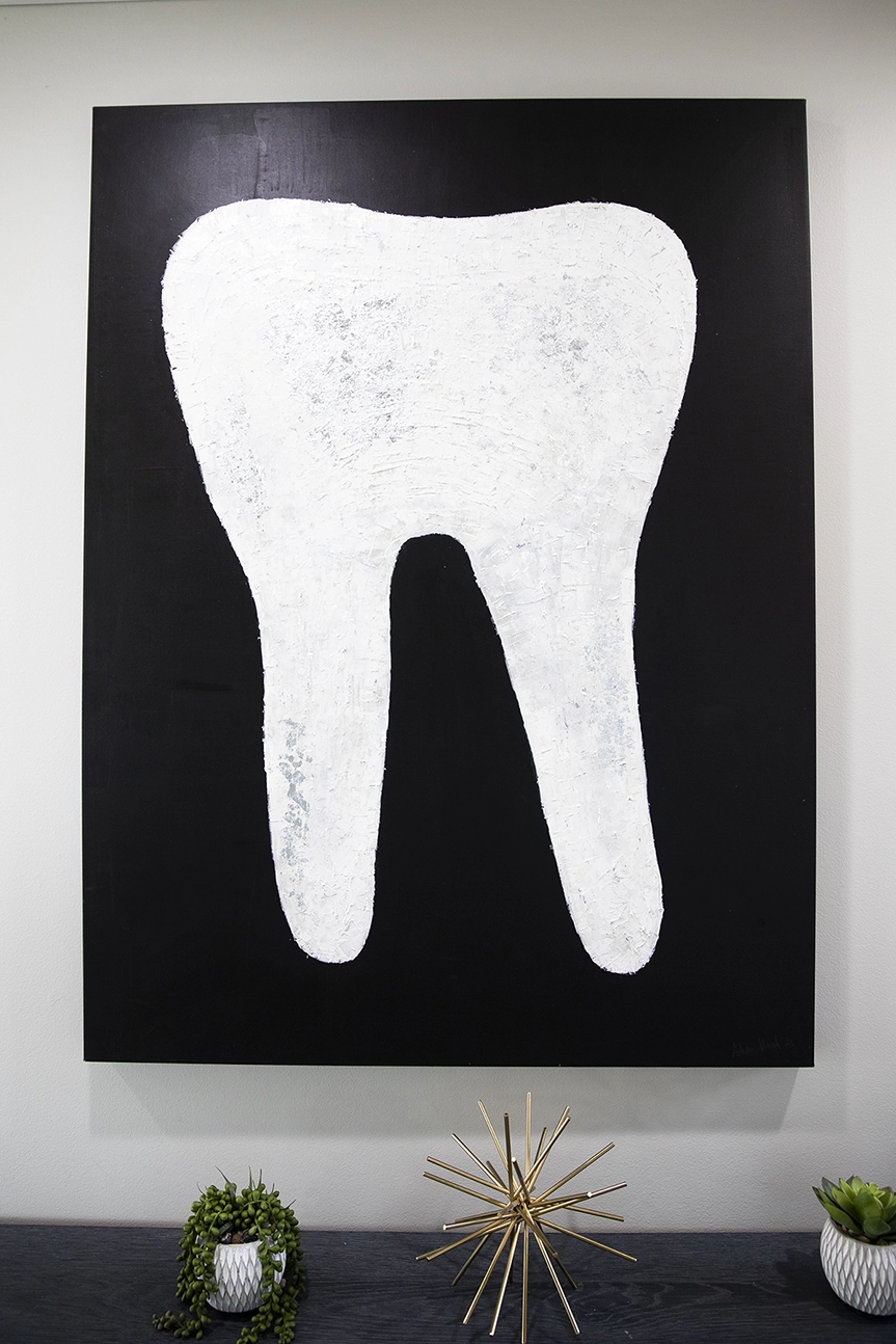 Painting of a white tooth on a black canvas.