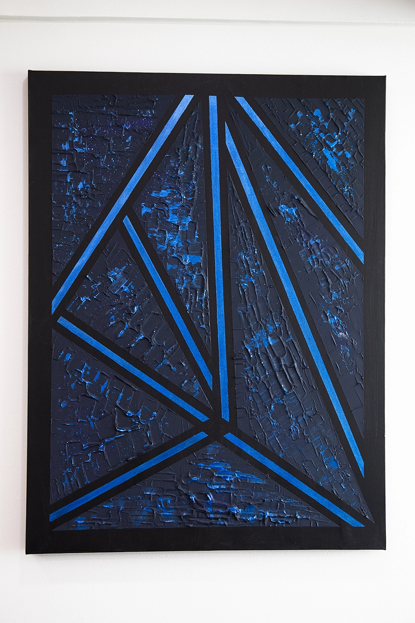 Abstract art piece of triangular blue shapes on a black canvas.