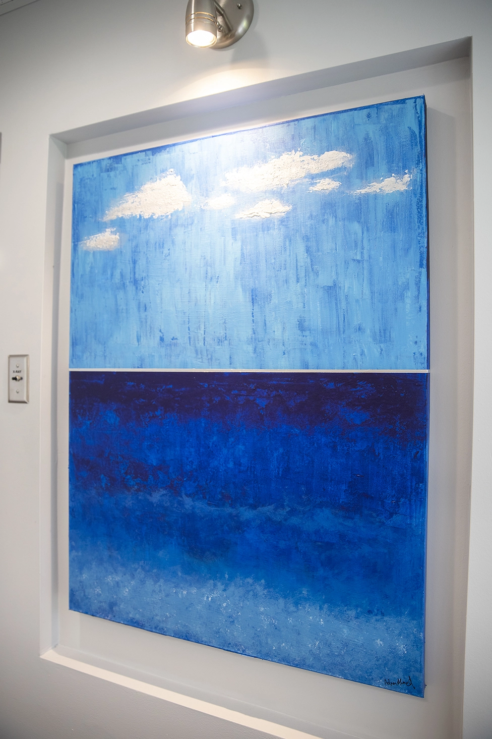 Blue abstract art piece that resembles the sky over the ocean, with clouds.