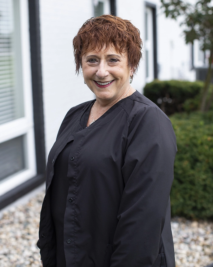 Portrait of Bonnie, Dental Hygienist from the waist up. Woman in hygienist uniform with red hair.