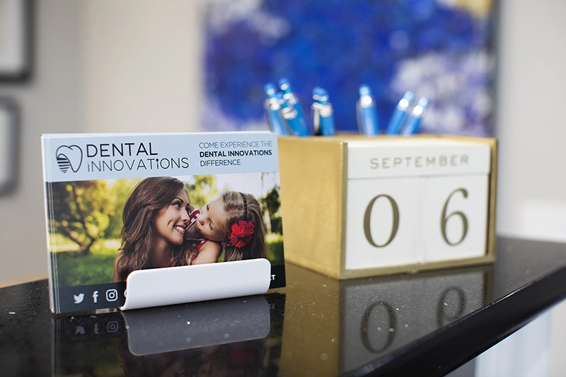Dental Innovations postcard, calendar blocks, and pen holder on a desk.