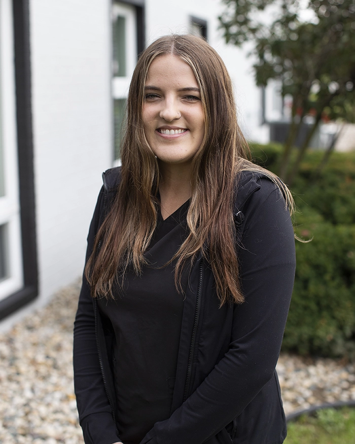 Portrait of Jaylyn, Business Team Member from the waist up. Woman in black uniform with brown hair.