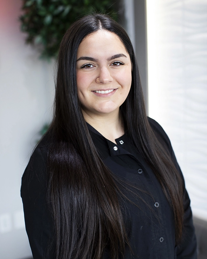 Portrait of Lydia, Dental Assistant from the waist up. Woman in black uniform with brown hair.