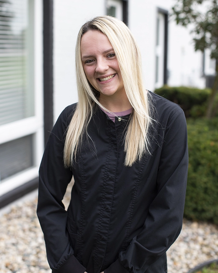 Portrait of Tara, Dental Assistant from the waist up. Woman in black uniform with blonde hair.