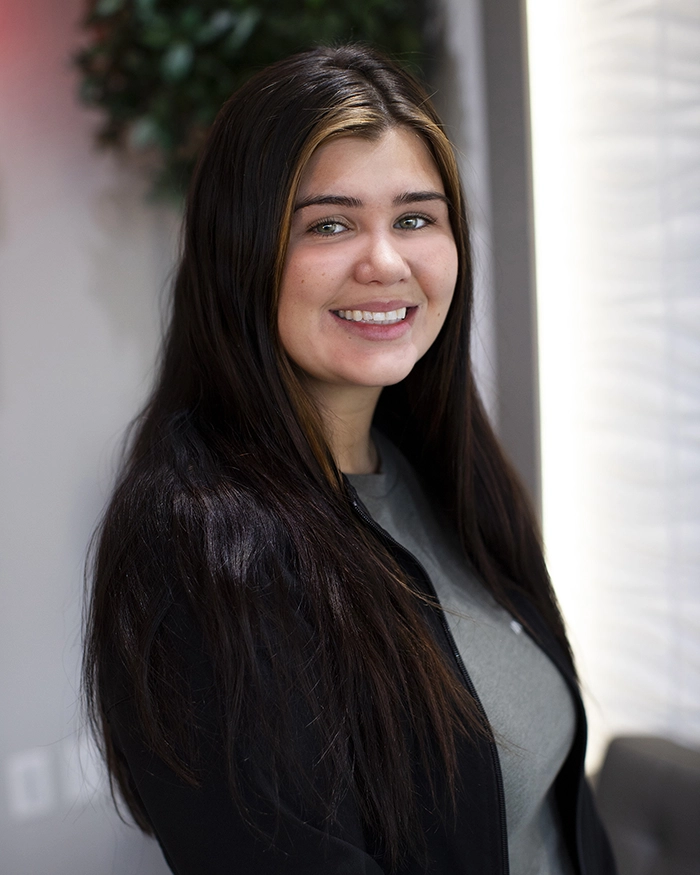 Portrait of Monica, Dental Assistant from the waist up. Woman in black uniform with brown hair.