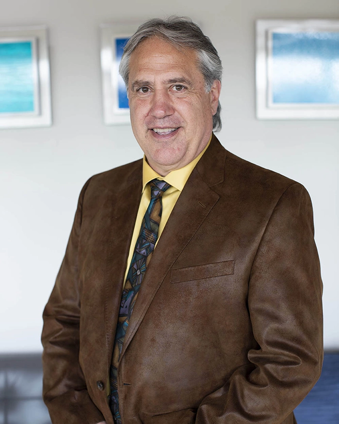 Portrait of Dr. Stanciu from the waist up. Wearing brown suit, yellow shirt, multi-colored tie.