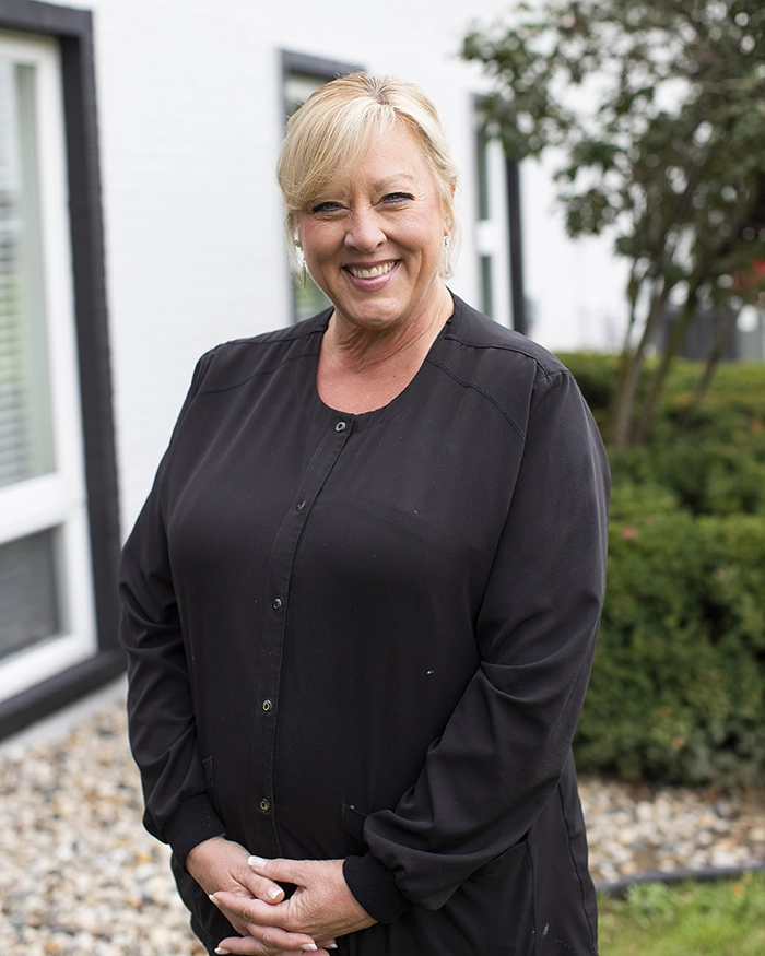 Portrait of Tracey, Dental Assistant from the waist up. Woman in black uniform with blonde hair.