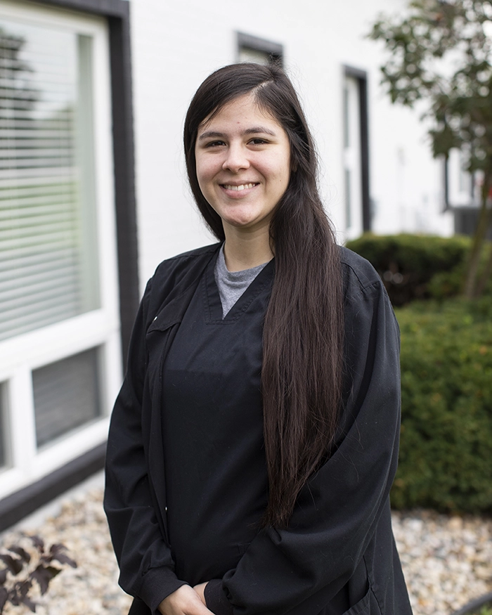 Portrait of Valenscia, Dental Assistant from the waist up. Woman in black uniform with brown hair.